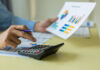 California Cannabis Tax Revenue Dips in Q4 2025 Person using a calculator beside printed charts, illustrating California cannabis tax revenue totals for Q4 2025.
