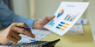 California Cannabis Tax Revenue Dips in Q4 2025 Person using a calculator beside printed charts, illustrating California cannabis tax revenue totals for Q4 2025.