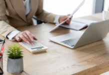 Cannabis Cash Management: What Banks Wish Operators Understood Business professional reviewing documents and using a calculator and laptop for financial reconciliation