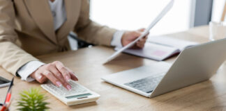 Cannabis Cash Management: What Banks Wish Operators Understood Business professional reviewing documents and using a calculator and laptop for financial reconciliation