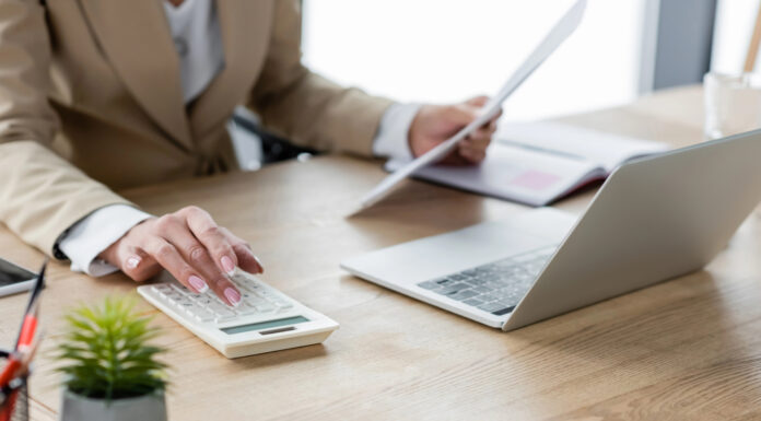 Cannabis Cash Management: What Banks Wish Operators Understood Business professional reviewing documents and using a calculator and laptop for financial reconciliation