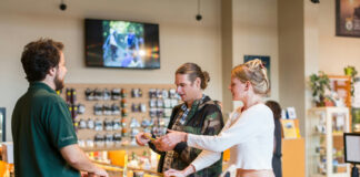 How to Choose the Right Cannabis Retail Business Model Customers consult a dispensary staff member at the counter while reviewing purchase options.