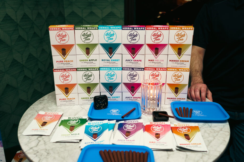 High Tea tobacco-free herbal wraps display with assorted flavors and sample wraps on trays.