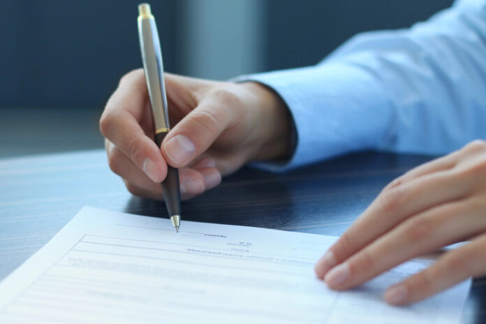 man's hand signing a contract