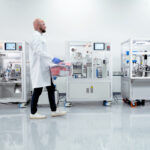 Vape Automation’s Missing Link Technician operating an automated vape cartridge packaging line in a clean manufacturing room.