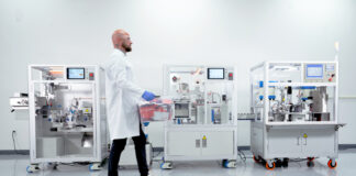 Vape Automation’s Missing Link Technician operating an automated vape cartridge packaging line in a clean manufacturing room.