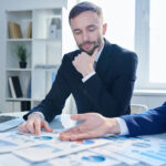 How to Build Cannabis Banking’s Missing Trust Layer A cannabis business operator and a banker discussing financial reports to build trust.