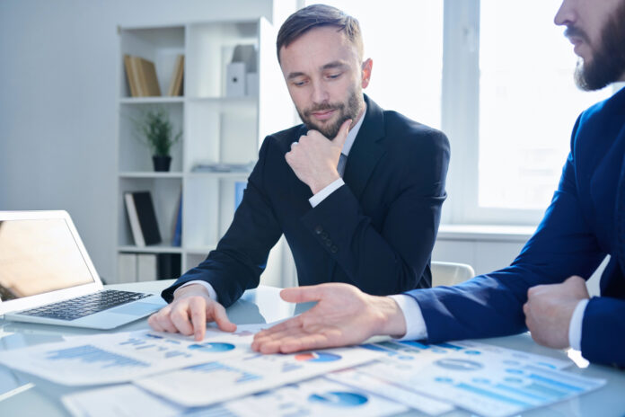 A cannabis business operator and a banker discussing financial reports to build trust.