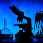 Rescheduling Cannabis: The Coming Collision with Ag-Biotech Regulation Silhouetted laboratory microscope, glass beakers, test tubes, pipettes, and sample bottles against a blue background for a cannabis biotechnology research story.