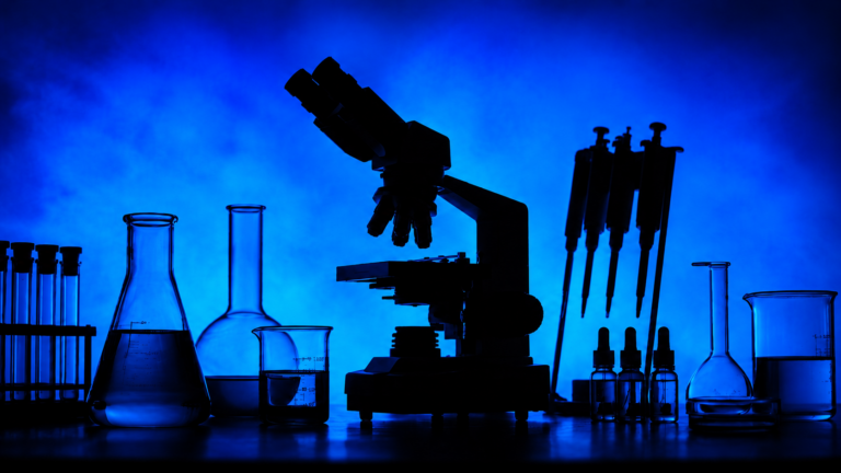 Silhouetted laboratory microscope, glass beakers, test tubes, pipettes, and sample bottles against a blue background for a cannabis biotechnology research story.