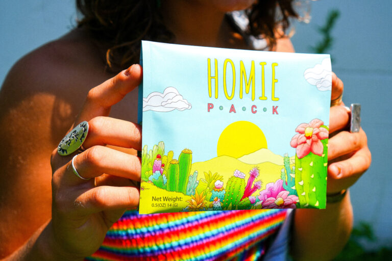 A person holds a colorful illustrated package featuring original cactus-and-flower artwork.