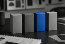 Cannabis Brands Need More Than Legacy, Passion, and Quality A vivid blue product box stands out among several gray boxes on a monochrome branding workspace.