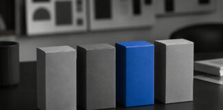 Cannabis Brands Need More Than Legacy, Passion, and Quality A vivid blue product box stands out among several gray boxes on a monochrome branding workspace.