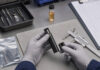 Vape Hardware Failures Cost More than a Replacement Technician inspecting an unbranded vape device at a cannabis hardware quality-control workstation