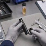 Vape Hardware Failures Cost More than a Replacement Technician inspecting an unbranded vape device at a cannabis hardware quality-control workstation