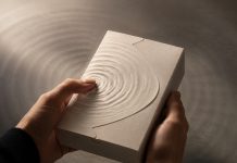 The Product Experience Begins Before the Package Opens Hands hold an unbranded textured package as ripples radiate from a fingertip.