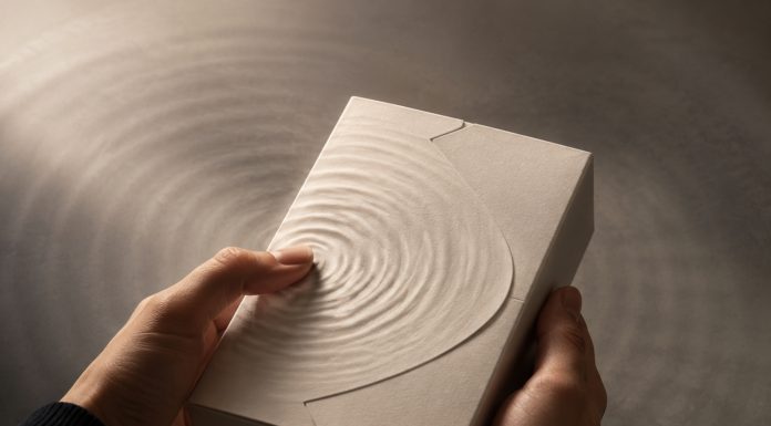 The Product Experience Begins Before the Package Opens Hands hold an unbranded textured package as ripples radiate from a fingertip.