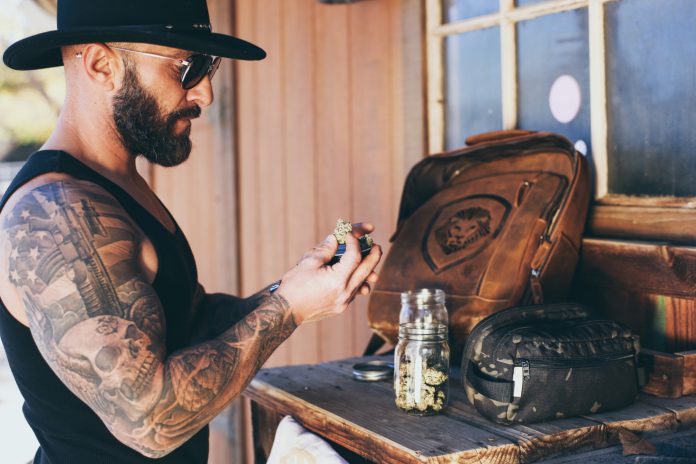 Sean Oganesyan examines flower Sean Oganesyan examines cannabis flower at a wooden workbench.
